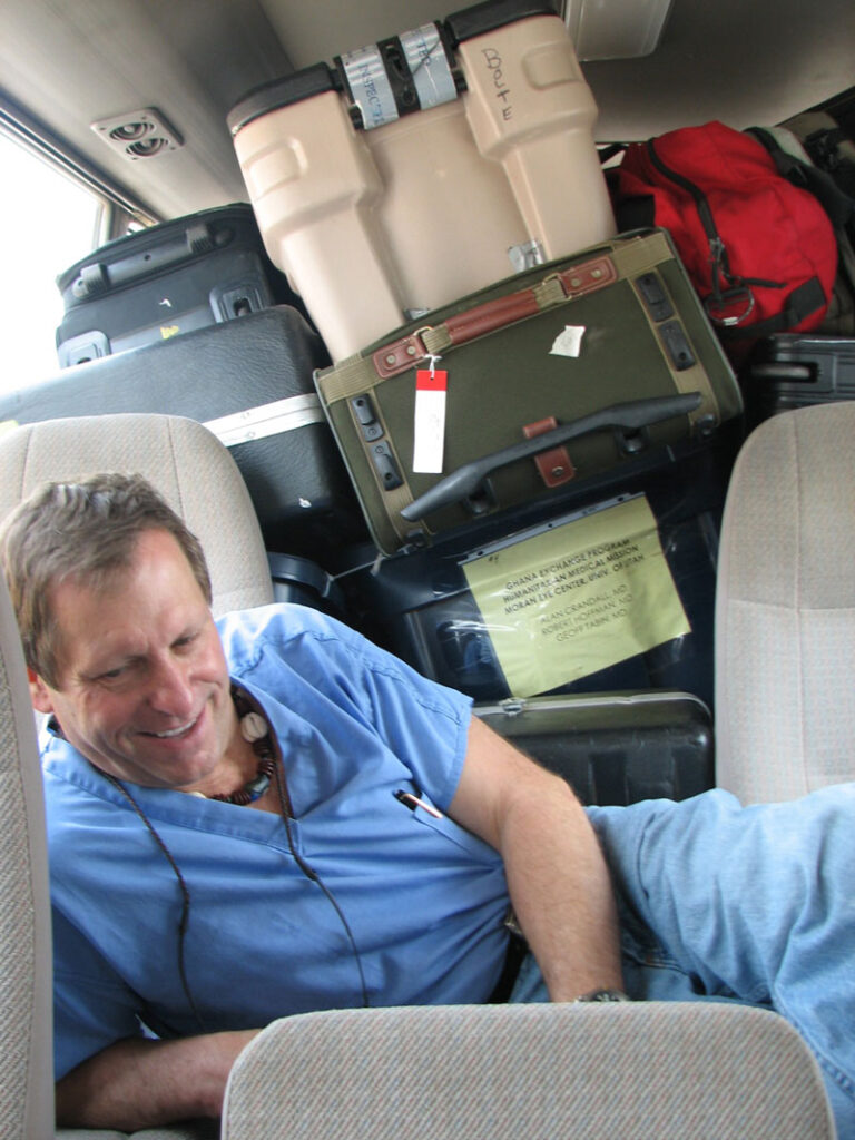Dr. Crandall sat among the luggage while on a mission trip. In a similar situation, a phaco  machine once fell on him,  causing him to fracture one  of the vertebrae in his neck.  He continued the mission work and sought care when he returned home. Source: Moran Eye Center/Flickr