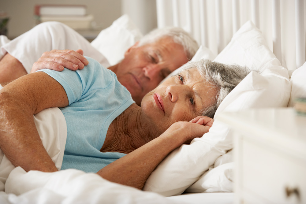 Elderly man and woman lying on their side in bed
