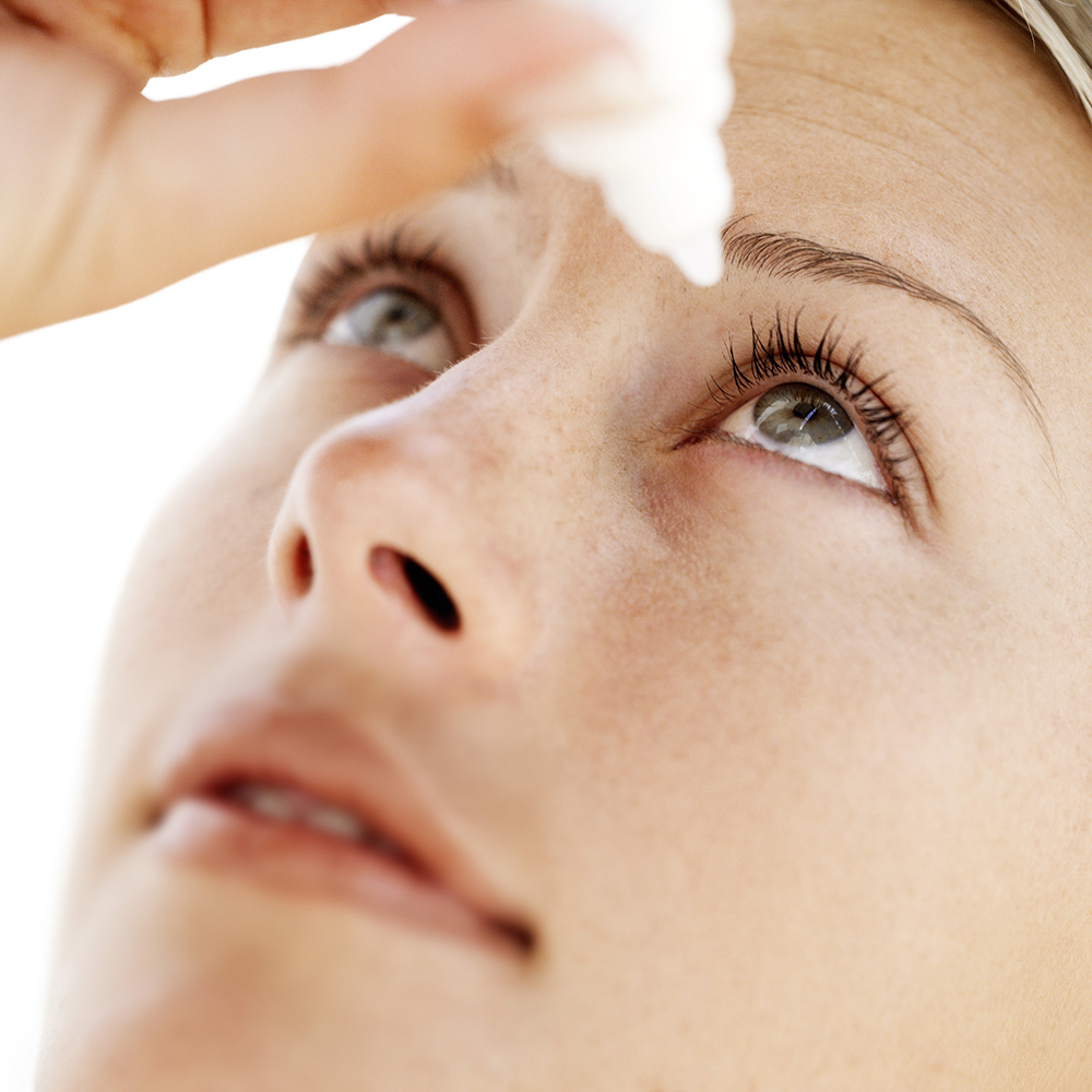 close-up of a young woman putting eye drops in eye